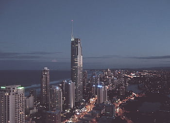 A mesmerizing cityscape at night featuring illuminated skyscrapers and a stunning skyline by the sea. HD wallpaper