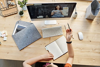 Teen girl actively learning in an organized home workspace via online class on a computer. HD wallpaper