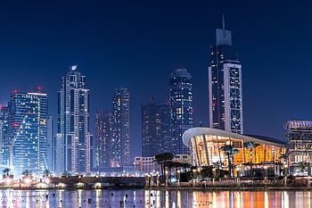 Stunning view of Dubai's illuminated skyline with modern skyscrapers reflecting on water at night. HD wallpaper