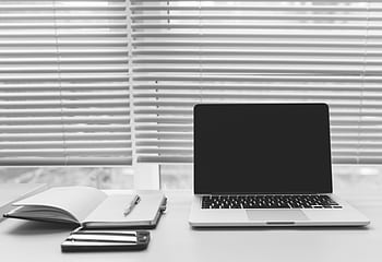 Minimalist black and white workspace featuring a laptop, notebook, and smart on a desk. HD wallpaper