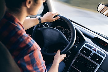 Close-up view of a man driving a modern car, showing dashboard and steering details. HD wallpaper