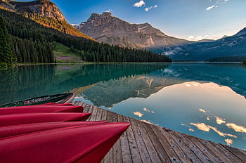 Vibrant red canoes on Emerald Lake with stunning mountain reflections at sunrise in British Columbia. HD wallpaper