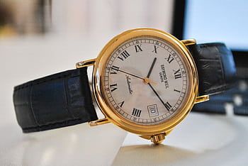 Close-up of a classic gold wristwatch with a black leather strap, showcasing time precision and elegance. HD wallpaper
