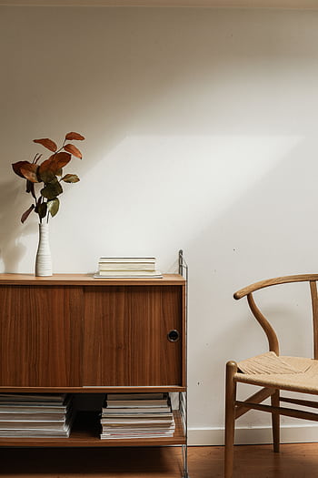 A serene minimalist interior design featuring a wooden sideboard and a ceramic vase. HD phone wallpaper