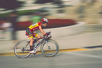 A cyclist in motion during a fast-paced race, highlighting speed and athleticism. HD wallpaper