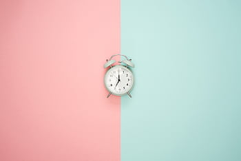 A vintage round clock on a split pastel pink and blue background. HD wallpaper