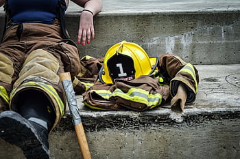Firewoman taking a break on concrete steps with gear and helmet nearby. HD wallpaper