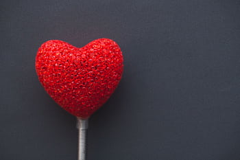 A vibrant red heart on a dark backdrop, symbolizing love and romance. HD wallpaper