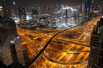 Stunning aerial view of Dubai's illuminated highways and skyscrapers at night. HD wallpaper