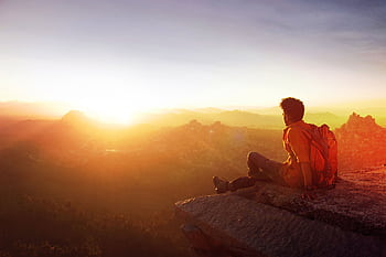 A man enjoys a breathtaking sunset view from a rocky cliff in Hampi, India. HD wallpaper