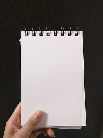 A close-up view of a hand holding a blank spiral notebook ready for writing or sketching. HD phone wallpaper