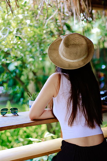 A woman wearing a straw hat enjoys a sunny day outdoors in Pakualaman, Jogja. HD phone wallpaper