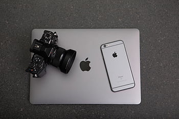 High-angle shot of DSLR camera, MacBook, and on textured surface, showcasing modern technology essentials. HD wallpaper