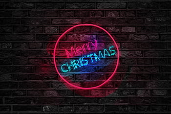 Vibrant neon Merry Christmas sign glowing on a dark brick wall, perfect for holiday themes. HD wallpaper