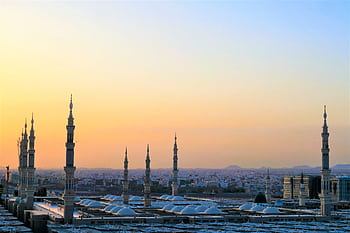 Stunning view of the Prophet's Mosque minarets at sunset in Medina, Saudi Arabia. HD wallpaper
