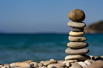 A stack of balanced stones on a beach with a tranquil ocean backdrop for meditation and zen. HD wallpaper