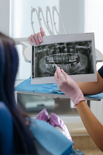 A dentist showing a dental X-ray to a patient in a clinic setting. HD phone wallpaper