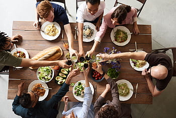 A vibrant group cheers over a delicious meal, showcasing friendship and togetherness. HD wallpaper