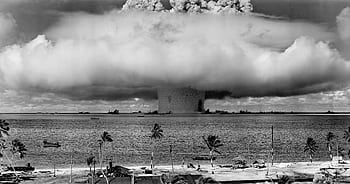 A black-and-white of a nuclear explosion seen from a tropical beach with coconut trees. HD wallpaper