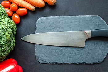 Close-up of fresh vegetables with a chef's knife on a rustic slate board. HD wallpaper