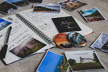 Travel diary surrounded by printed and a pen, capturing memories creatively. HD wallpaper