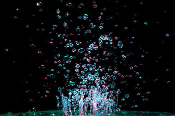 Captivating close-up of water droplets captured mid-splash against a dark background, showcasing fluid dynamics. HD wallpaper