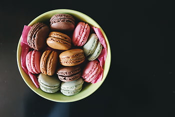 A vibrant assortment of macarons in a green bowl, perfect for dessert themes. HD wallpaper