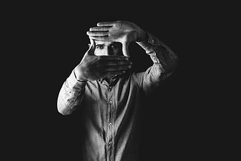 Black and white portrait of a man framing his face with his hands, creating an artistic, moody effect. HD wallpaper