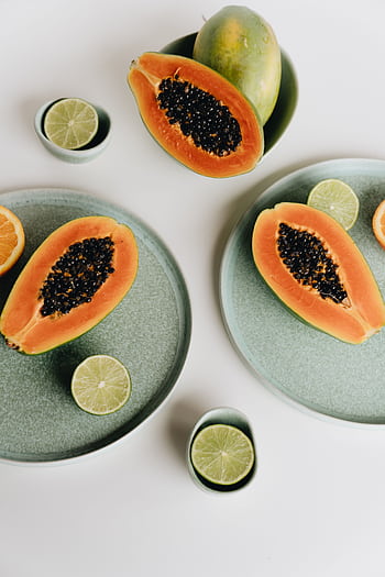Vibrant of sliced papaya and lime on pastel plates, highlighting freshness. HD phone wallpaper