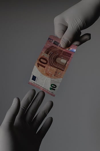 Sterile transaction concept with gloved hands exchanging a 10 Euro note. HD phone wallpaper