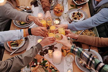 A warm, festive dinner party with friends clinking glasses over a candlelit table. HD wallpaper