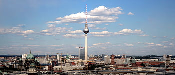 Panoramic view of Berlin's skyline with Fernsehturm TV tower under a clear blue sky. HD wallpaper