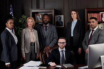 A diverse group of business professionals posing in an office, showcasing teamwork and leadership. HD wallpaper