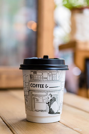 A close-up of a to-go coffee cup with panda art in a cozy cafe setting. HD phone wallpaper