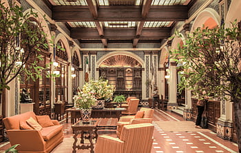 A luxurious hotel lobby featuring elegant architecture, rich decor, and comfortable seating under a stained glass ceiling. HD wallpaper