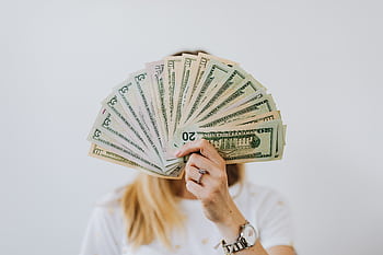Close-up of a person holding a fan of US dollar bills on a neutral background. HD wallpaper