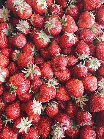A vibrant close-up of fresh, juicy red strawberries with green leaves. HD phone wallpaper