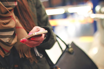 Close-up of a woman using a smart indoors, wearing a stylish scarf and coat. HD wallpaper