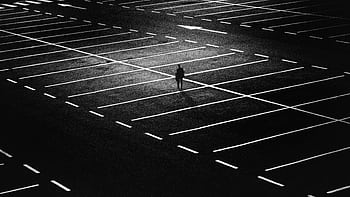 Silhouette of a solitary figure in an expansive night-time parking lot. HD wallpaper