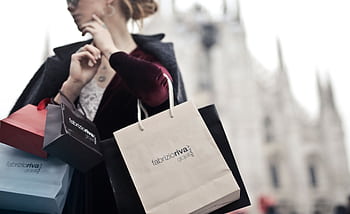 Stylish woman holding designer shopping bags near Milan's iconic Duomo. Urban fashion and lifestyle concept. HD wallpaper