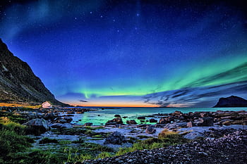 Stunning Northern Lights display over a coastal landscape during night. HD wallpaper