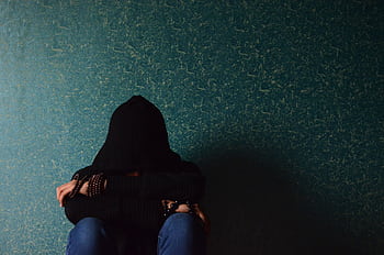 A person sits alone in a hoodie, conveying a sense of solitude and introspection. HD wallpaper