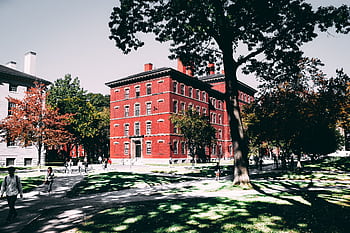 View of a historic red brick university building surrounded by lush trees and walking paths. HD wallpaper