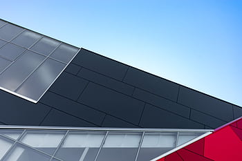 A modern building facade with geometric glass and steel patterns against a clear sky. HD wallpaper
