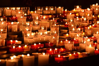 Rows of flickering candles in a chapel setting, evoking tranquility and reflection. HD wallpaper