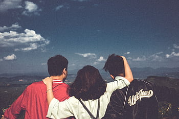A group of three friends embracing and enjoying the scenic mountain view in Đắk Ya, Vietnam. HD wallpaper