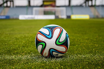 A vibrant adidas soccer ball on a green field, perfect for sports enthusiasts. HD wallpaper