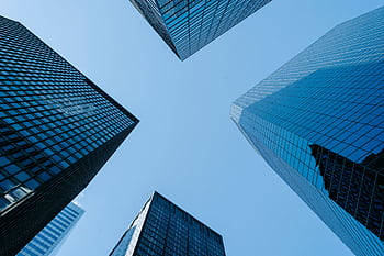 A low-angle view of modern skyscrapers with glass facades against a clear blue sky. HD wallpaper