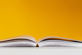 A close-up shot of an open book with a vivid yellow background, perfect for creative and conceptual design. HD wallpaper