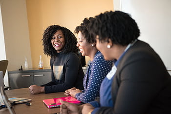 Three black women in a happy office meeting, engaging in teamwork. HD wallpaper